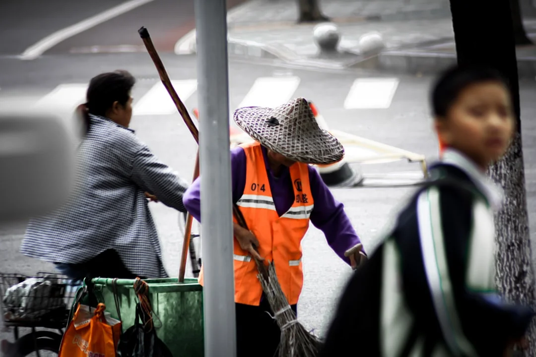 Un agent nettoie les vitres d’un gratte-ciel avec un harnais dans un environnement urbain.